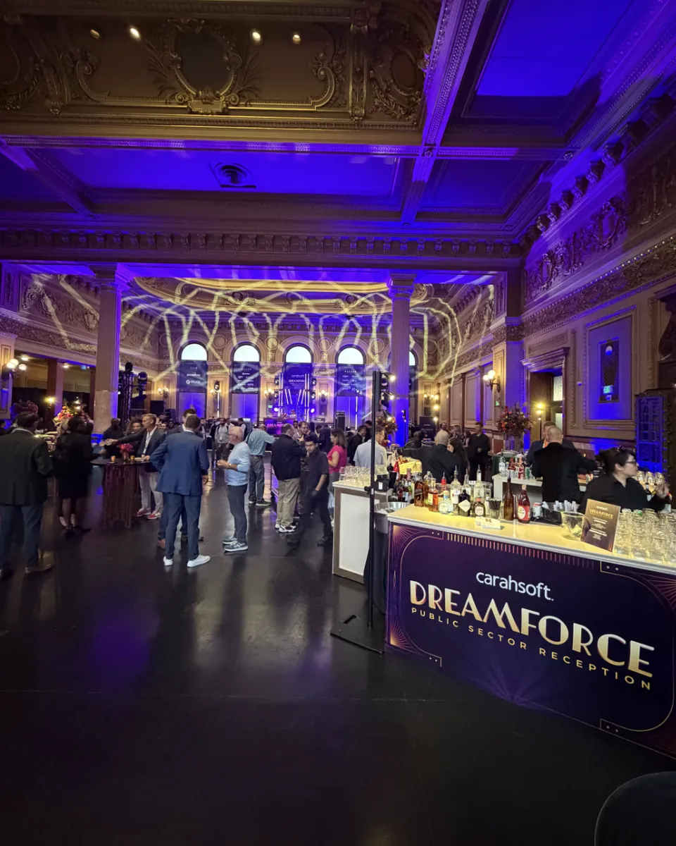 Guests at the Carahsoft Dreamforce Public Sector Reception in the ballroom of The Hibernia, San Francisco, with the Carahsoft-branded bar in the foreground